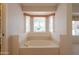 Comfortable soaking tub with integrated seat and neutral design, set under a bright window at 2422 E Rockledge Rd, Phoenix, AZ 85048