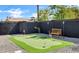 Well-manicured backyard putting green and a bench next to a brick fence, perfect for outdoor activities at 2509 E Meadowbrook Ave, Phoenix, AZ 85016