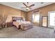 Cozy carpeted main bedroom with a decorative ceiling fan, a wooden bed frame, and a sun-filled window at 2699 E Claxton Rd, Gilbert, AZ 85297