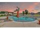 Inviting pool area with a rock waterfall feature, palm trees, and string lights for an evening ambiance at 2699 E Claxton Rd, Gilbert, AZ 85297