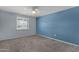 Light-filled bedroom features neutral carpet, blue accent wall, and bright, shuttered window at 3825 E Captain Dreyfus Ave, Phoenix, AZ 85032