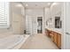 Bright bathroom with dual sinks, a glass block partition, and a large soaking tub at 41903 N Golf Crest Rd, Anthem, AZ 85086