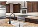 Close-up of a kitchen featuring custom cabinets, granite countertops, stainless steel appliances, and tiled backsplash at 41903 N Golf Crest Rd, Anthem, AZ 85086