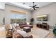 Bright living room with a large sectional sofa, entertainment center, and expansive windows with backyard views at 41903 N Golf Crest Rd, Anthem, AZ 85086