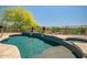 Inviting pool with baja shelf and elevated spa; surrounded by desert landscaping and wrought iron safety fence at 41903 N Golf Crest Rd, Anthem, AZ 85086