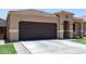 Charming single-story home featuring a desert landscape, brown garage door, and tiled roof at 41903 W Rojo St, Maricopa, AZ 85138