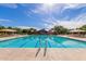 Community pool with marked lanes for exercise, surrounded by trees and sun umbrellas for shaded relaxation at 4662 S Calico Rd, Gilbert, AZ 85297
