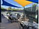 Covered outdoor seating area near the tennis courts with tables, chairs, and string lights at 7222 E Gainey Ranch Rd # 232, Scottsdale, AZ 85258