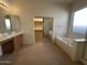 This primary bathroom features a soaking tub, large mirror, and walk-in closet at 7227 W Paradise Ln, Peoria, AZ 85382