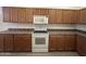 A kitchen with wooden cabinets, an electric stove, microwave, and neutral countertops at 7227 W Paradise Ln, Peoria, AZ 85382