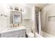 Neat bathroom with a single sink vanity, framed mirror, and a shower/tub combination with a patterned shower curtain at 9028 E Altadena Ave, Scottsdale, AZ 85260