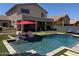 Resort-style backyard featuring pool with baja step, covered patio, and artificial grass at 10430 W Los Gatos Dr, Peoria, AZ 85383