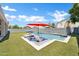 Stylish backyard pool and lounge area, complete with a bright red umbrella and chaise lounges on artificial turf at 10430 W Los Gatos Dr, Peoria, AZ 85383