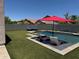 Backyard oasis featuring a pool with baja step, lounge chairs and artificial grass at 10430 W Los Gatos Dr, Peoria, AZ 85383