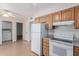 Wide view of kitchen featuring wood cabinets, white appliances and an adjacent laundry area at 10520 W Coggins Dr, Sun City, AZ 85351