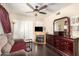 Spacious main bedroom featuring a fireplace, ceiling fan, hardwood floors, and an updated dresser with mirror at 10820 N 45Th Dr, Glendale, AZ 85304