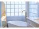 Close-up of a sleek white standalone tub with gold fixtures and a glass block window at 11089 N 130Th Pl, Scottsdale, AZ 85259