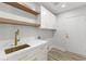 Laundry room with marble countertops, brass faucet, white cabinets, and open shelving at 11089 N 130Th Pl, Scottsdale, AZ 85259