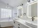 Luxurious bathroom featuring double sinks, stylish lighting, and a contemporary soaking tub at 1616 N 125Th Ln, Avondale, AZ 85392