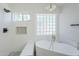 Elegant bathroom featuring a soaking tub, glass block window, and modern fixtures at 1616 N 125Th Ln, Avondale, AZ 85392