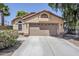 Tan single-story home featuring a two-car garage and low maintenance desert landscaping at 1616 N 125Th Ln, Avondale, AZ 85392