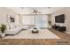 Bright living room featuring a white sofa, modern decor, and wood-look tile flooring at 18108 W Cassia Way, Goodyear, AZ 85338