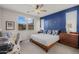 Bedroom features a blue accent wall, ceiling fan, and a cozy sitting area next to the window at 20904 E Swan Dr, Queen Creek, AZ 85142