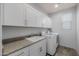 Functional laundry room with sleek white cabinets, sink, and modern washer/dryer at 20904 E Swan Dr, Queen Creek, AZ 85142