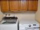 Laundry room with front loading washer and dryer, with wooden cabinets above at 211 Bahia E Ln, Litchfield Park, AZ 85340