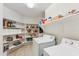 Bright laundry room featuring abundant built-in shelving and white appliances at 2432 W Oberlin Way, Phoenix, AZ 85085