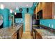 Kitchen features stainless steel appliances, granite countertops, island bar and teal blue walls at 26475 N Wrangler Rd, Scottsdale, AZ 85255