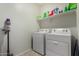 Bright laundry room features a white washer and dryer, along with convenient shelving at 3026 N 305Th Dr, Buckeye, AZ 85396