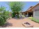 Backyard featuring a brick fire pit, covered patio, mature trees, and views of the home's exterior at 4609 W Challenger Trl, New River, AZ 85087