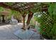 Backyard patio area with a grill, dining table, and pergola with vine growth at 4609 W Challenger Trl, New River, AZ 85087