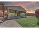 A covered patio with ceiling fans sits on a grassy yard, extending from a home with sunset hues in the sky at 4866 N 185-Th Dr, Goodyear, AZ 85395