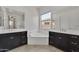 Luxurious bathroom with dual sinks, a soaking tub, dark wood cabinets, and bright natural light at 4866 N 185-Th Dr, Goodyear, AZ 85395
