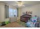 Bedroom featuring a crib, dresser and a large window for a cozy atmosphere at 5911 E Evergreen St, Mesa, AZ 85205
