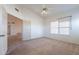 An open bedroom with neutral carpet, a ceiling fan, a large window, and an doorway to another room at 7531 W Kimberly Way, Glendale, AZ 85308