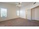 A large bedroom featuring neutral carpet, bright windows, a ceiling fan, and a door that leads to another room at 7531 W Kimberly Way, Glendale, AZ 85308