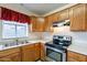 Cozy kitchen with stainless oven, wood cabinets, tile floors, and double sink at 7531 W Kimberly Way, Glendale, AZ 85308
