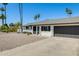 Beautiful one story white brick house featuring a dark garage door, gravel yard and mature landscaping at 9214 N 54Th Ave, Glendale, AZ 85302