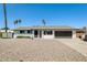 Charming single-story home features a gravel yard, black garage door, and palm trees in a sunny setting at 9214 N 54Th Ave, Glendale, AZ 85302