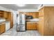 Kitchen with wooden cabinets, stainless steel refrigerator, and an adjacent laundry area at 9214 N 54Th Ave, Glendale, AZ 85302