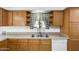 Traditional kitchen with wood cabinets, double sink, and a window with decorative curtains and shelving at 9214 N 54Th Ave, Glendale, AZ 85302