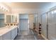 Bright bathroom featuring a double sink vanity, framed mirrors, tiled shower, and a walk-in closet with decorative tile accents at 10305 E Dragoon Ave, Mesa, AZ 85208