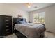A well-lit bedroom boasts neutral-toned walls, a ceiling fan, a cozy bed, and a dark dresser and floors at 10305 E Dragoon Ave, Mesa, AZ 85208