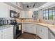 Charming kitchen with white cabinetry, a black range, and tile countertops for functionality at 14420 N 44Th Dr, Glendale, AZ 85306