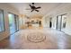 Open concept living room with tile flooring, ceiling fan, and views into the kitchen and outdoor spaces at 22903 N 39Th Ter, Phoenix, AZ 85050