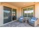 Covered patio area with comfortable blue wicker chairs and a sliding glass door leading to the home at 22920 E Indiana Ave, Queen Creek, AZ 85142