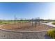Community playground featuring swings and climbing structure, set on a mulch base and adjacent to walking path at 22920 E Indiana Ave, Queen Creek, AZ 85142
